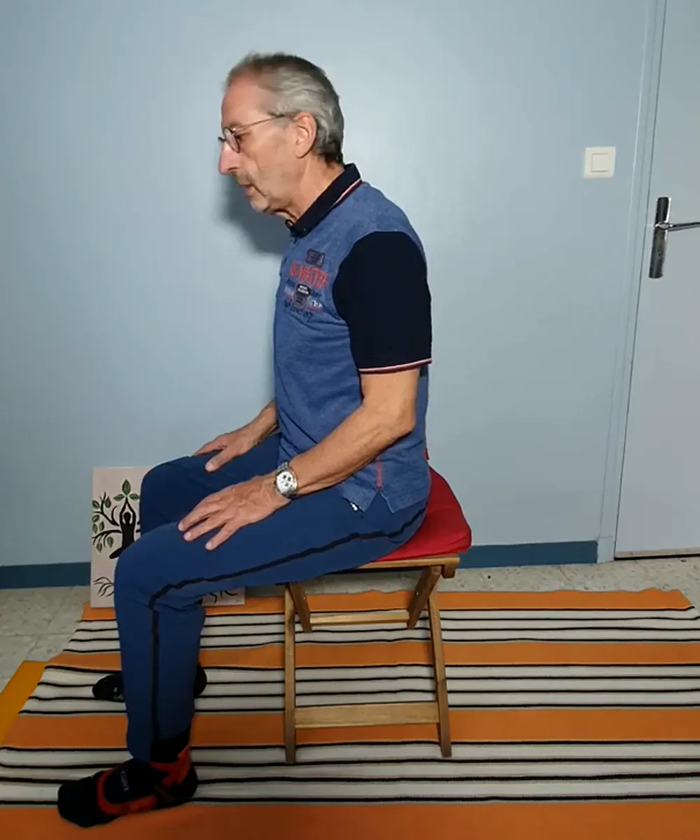 Jean-Louis Sitjar assis de profil sur un tabouret, le dos droit